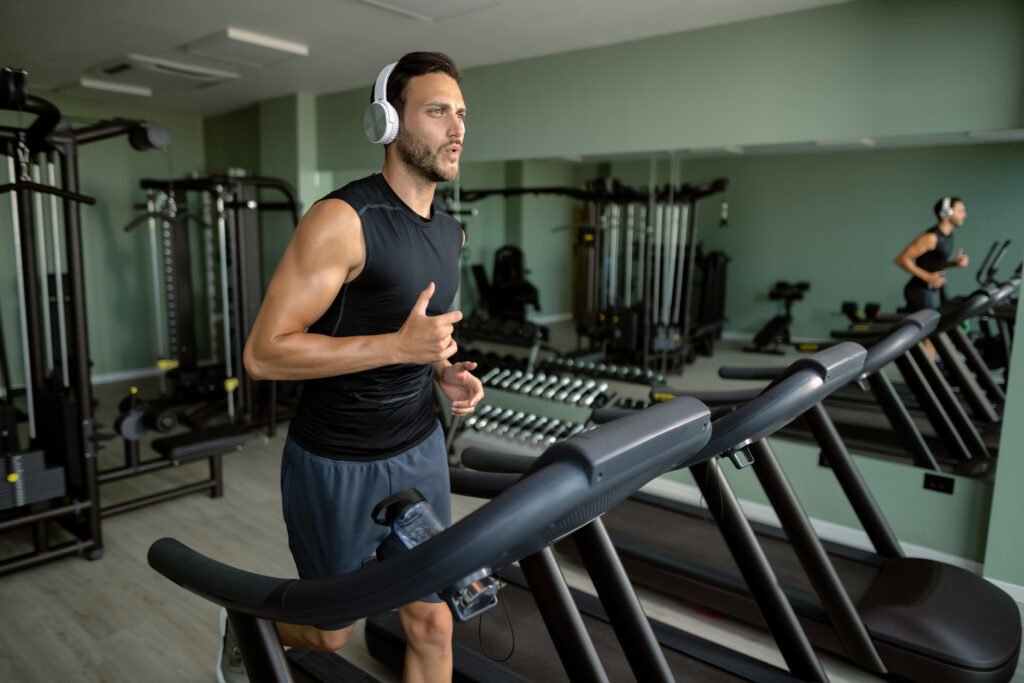 young athletic man running treadmill gym
